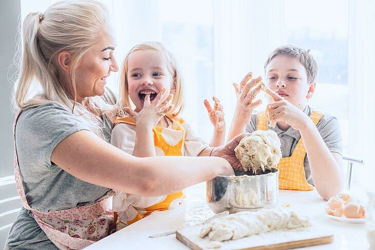 Mère et enfants préparent une pâte à gâteau à la maison, activité manuelle et gourmande.