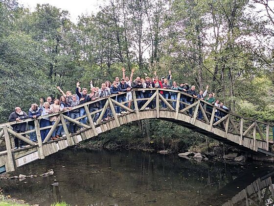 Photo de groupe des adhérents du réseau Sites et Paysages réunis sur un pont en bois au cœur de la nature, à l'occasion du congrès annuel.