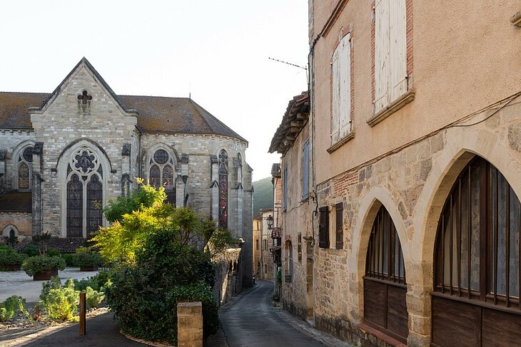 Patrimoine de Saint-Antonin-Noble-Val et centre ancien Ruelle du centre ancien de Saint-Antonin-Noble-Val bordée de maisons en pierre, avec l’église Saint-Antonin en arrière-plan.