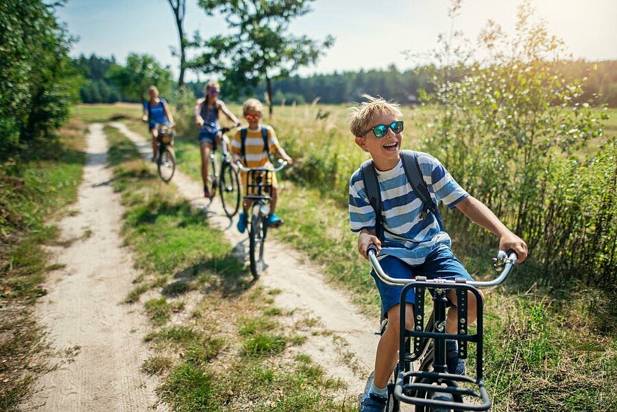 Enfants souriants à vélo sur un chemin de campagne dans le Loir-et-Cher, séjour nature en camping familial
