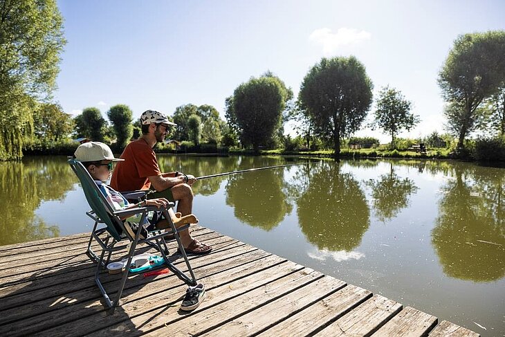 Père et fils profitant d’un moment de pêche au bord d’un étang à Brissac Loire Aubance, dans un cadre naturel paisible entre eau et verdure.