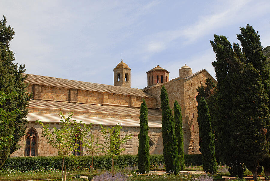 Abbaye romane entourée de cyprès, représentative du patrimoine historique à découvrir lors d’un séjour en camping au cœur de l’Aude.