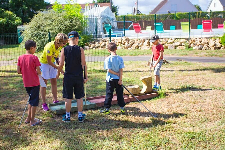 Enfants jouant au mini-golf sous la supervision d’une animatrice dans un camping familial près de la Sologne, à Gien.
