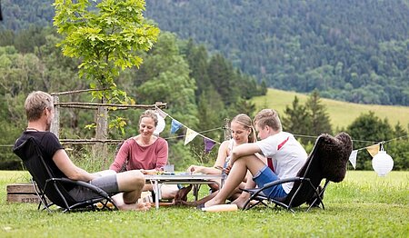 Famille réunie autour d’un jeu en pleine nature, incarnant les valeurs du tourisme durable promues dans le guide du vacancier responsable de Sites et Paysages.