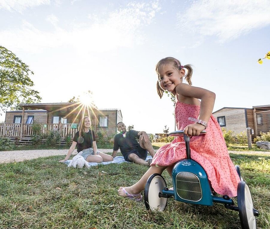 Famille profitant d’un moment de détente devant un chalet en bois dans un camping près de Rocamadour, idéal pour des vacances en pleine nature.