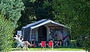 Emplacement de camping spacieux et ombragé, entouré de verdure, idéal pour des vacances en pleine nature.