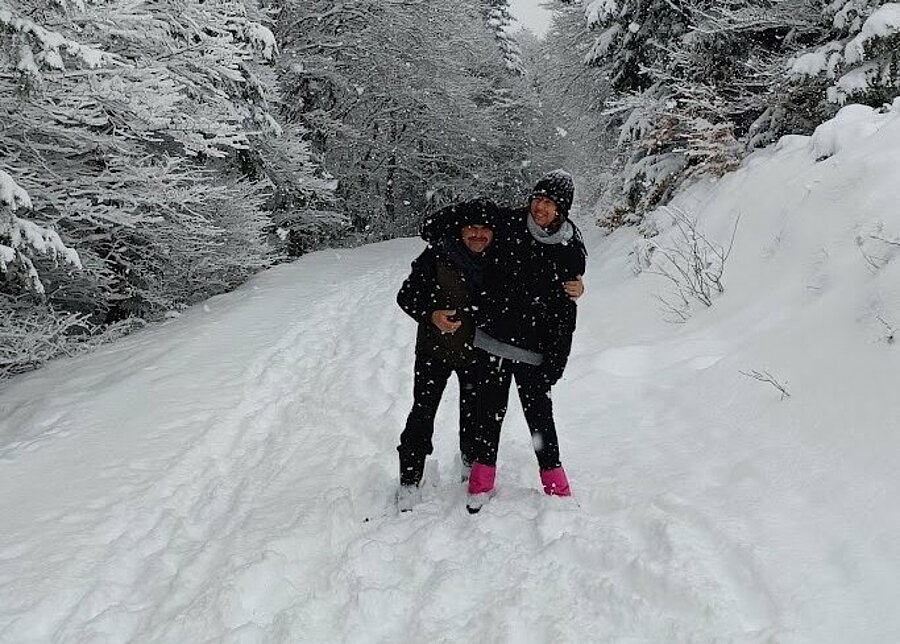 Couple en balade sur un chemin enneigé en forêt, ambiance sports d’hiver et nature, idéal pour des vacances en camping hiver.