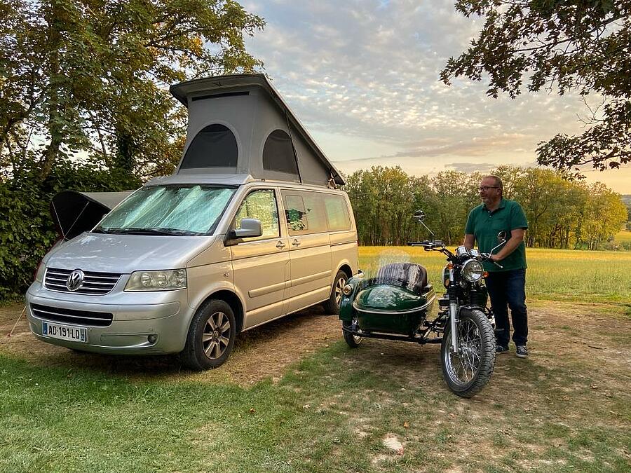 Homme avec son side-car à côté d'un van sur un emplacement spacieux