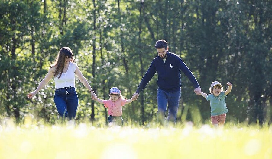 Famille avec enfants marchant main dans la main dans un cadre naturel au camping, idéale pour réserver un week end famille.