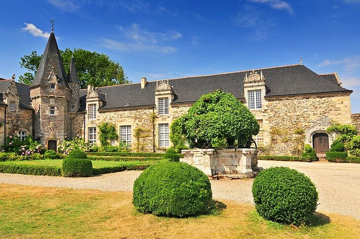 Façade du château de Rochefort-en-Terre entourée de jardins fleuris, étape incontournable lors d’une visite de Rochefort en Terre dans le Morbihan.