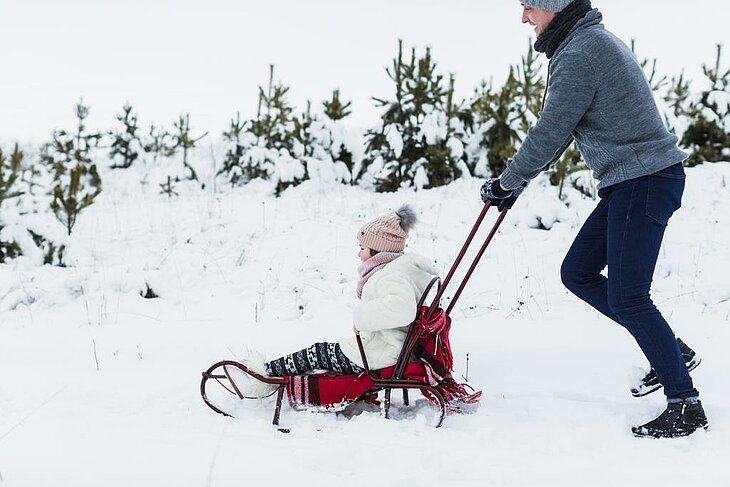 Un père et sa fille profitent des joies de l’hiver en faisant de la luge dans un paysage enneigé près de La Bourboule. Une activité incontournable pour s’amuser en famille lors d’un séjour hivernal en Auvergne.