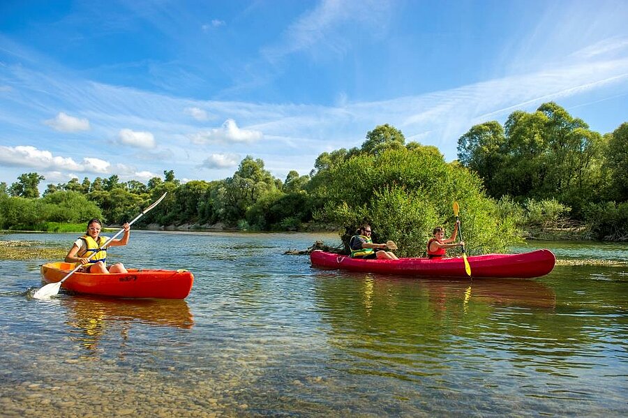 Famille en canoë sur une rivière en pleine nature, profitant d’activités grâce aux frais de dossier offerts dans un camping pas cher.