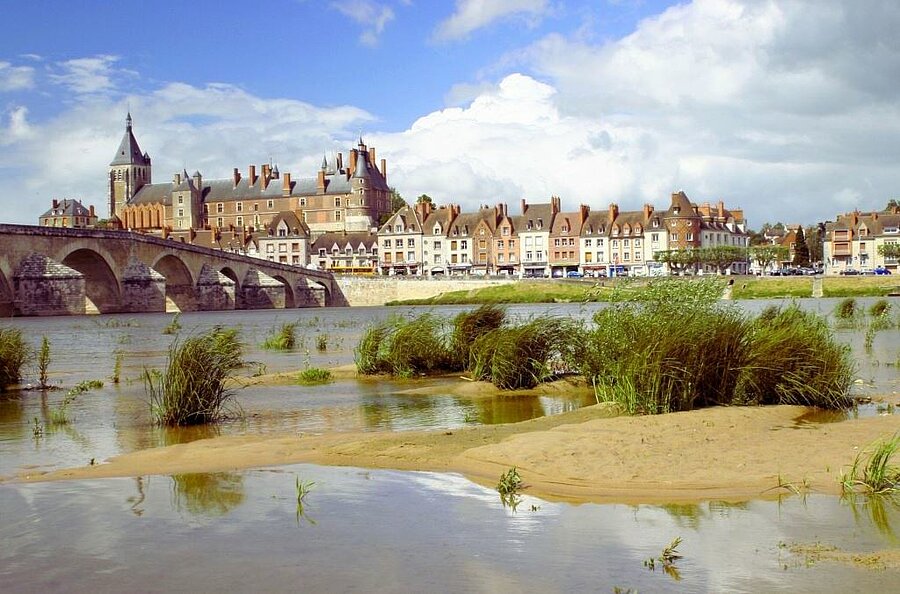 Vue panoramique sur le château de Gien et la Loire, avec son pont en pierre historique, un site incontournable à découvrir lors d’un séjour en camping près de Gien.