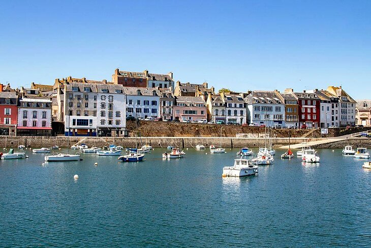 Bateaux de plaisance amarrés dans le port de Douarnenez, avec les maisons colorées en arrière-plan.