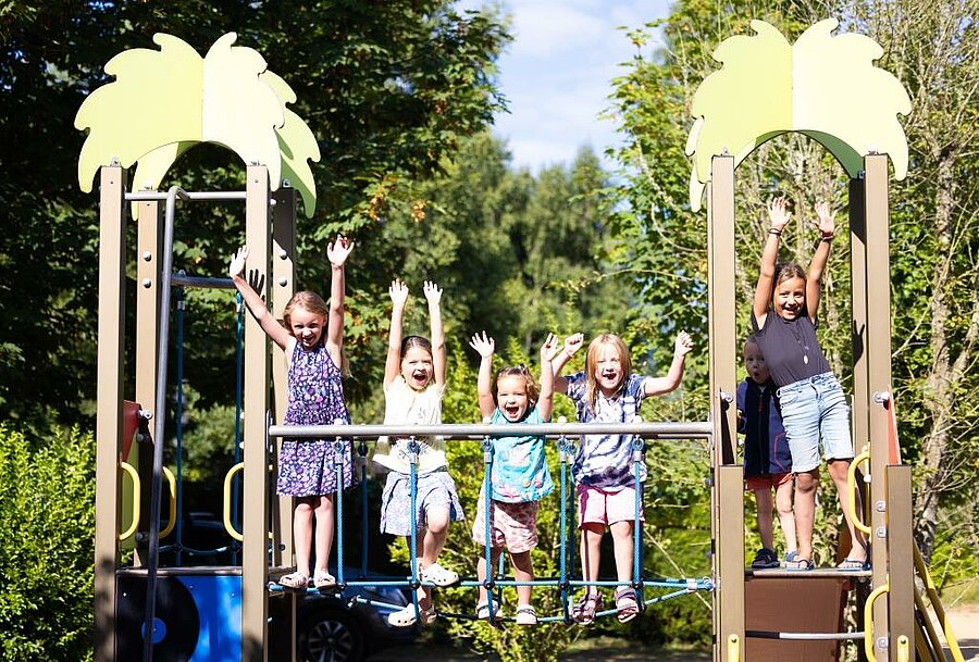 Enfants s’amusant sur une aire de jeux en plein air dans un camping des Côtes d’Armor, idéal pour des vacances familiales en Bretagne
