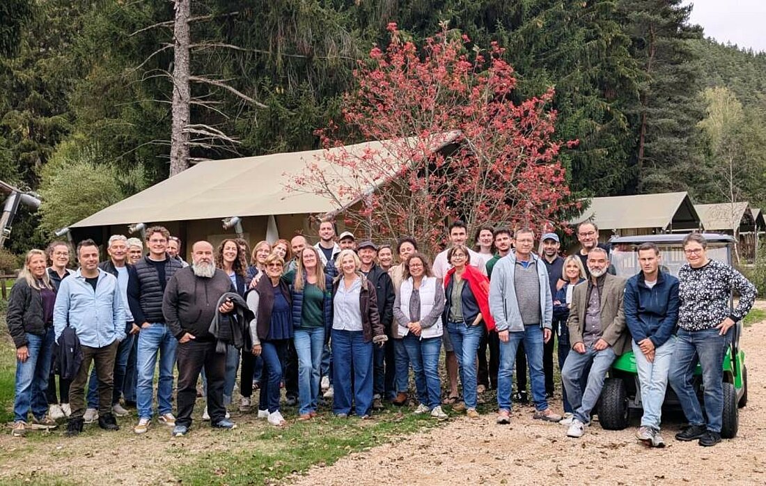 Photo de groupe des propriétaires et membres du réseau Sites et Paysages réunis devant des hébergements toilés, lors du congrès annuel au Camping de Vaubarlet en Haute-Loire.