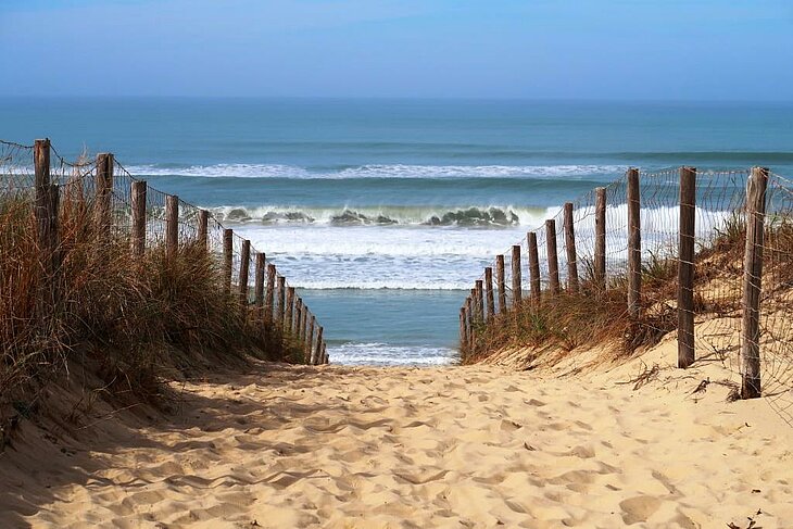 Accès à une plage de sable fin face à l’océan Atlantique, destination emblématique du tourisme en Nouvelle-Aquitaine.