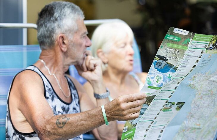 Préparer son séjour en camping en arrière-saison Couple consultant une carte touristique pour préparer ses découvertes pendant un séjour en camping