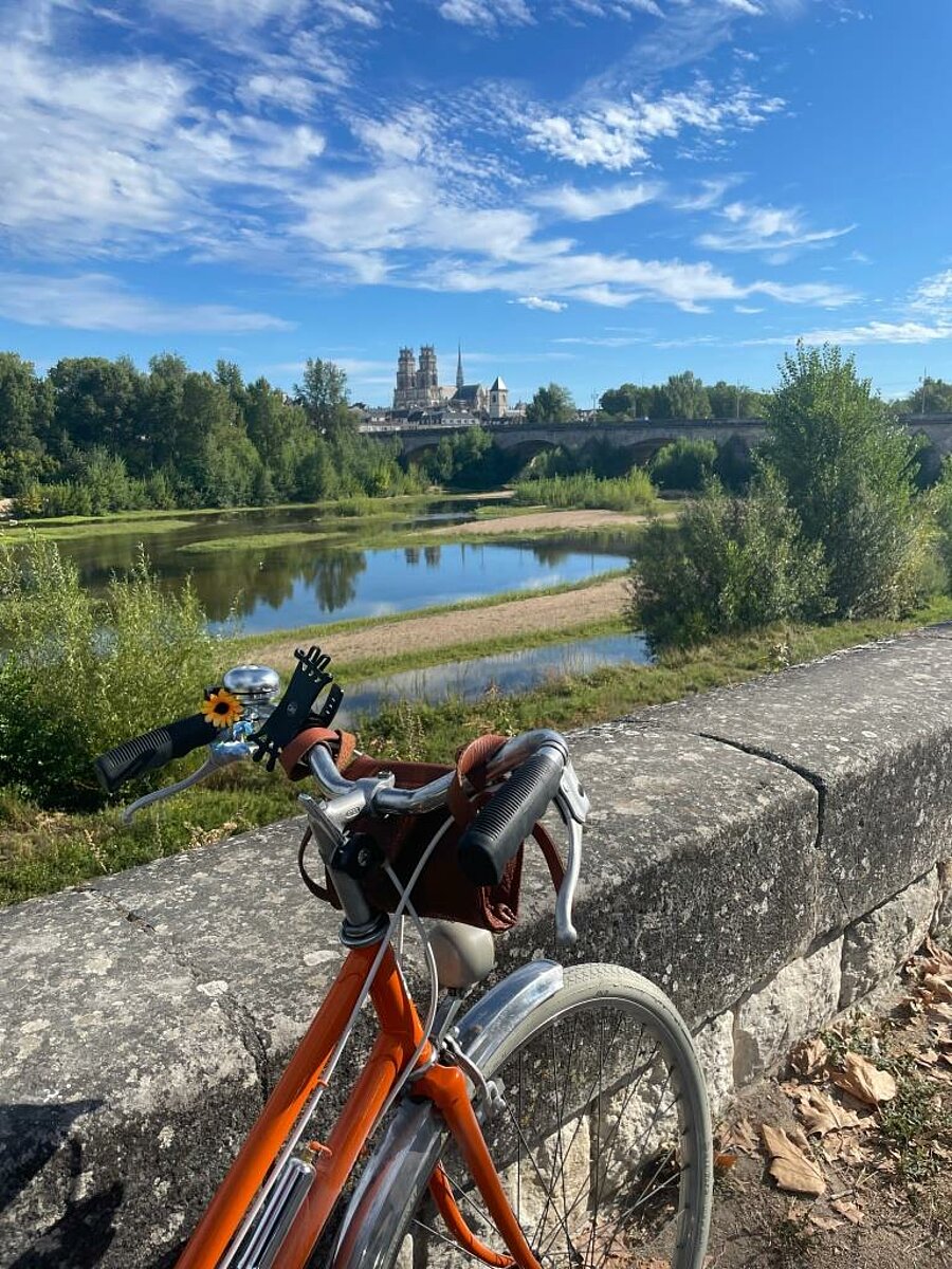 Balade à vélo le long de la Loire avec vue sur la cathédrale d'Orléans, une expérience incontournable lors d'un séjour en camping dans le Centre-Val de Loire.