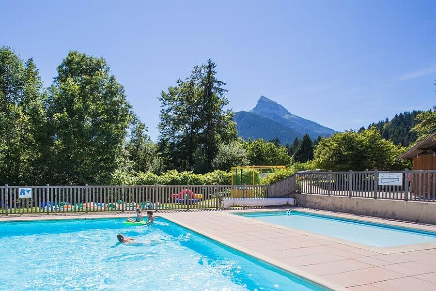 Piscine en plein air dans un camping en Isère, avec vue sur les montagnes de la Chartreuse, offrant un cadre idéal pour des vacances en famille alliant détente et nature.