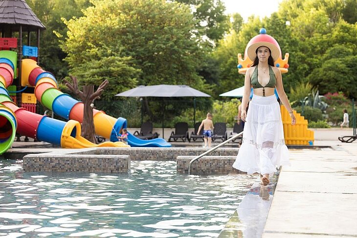 Piscine et toboggans aquatiques au camping Une vacancière marche au bord de la piscine d’un camping avec des toboggans aquatiques.
