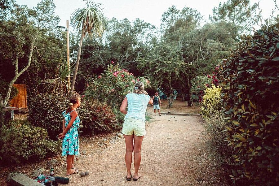 Famille jouant à la pétanque dans un cadre naturel et convivial au sein d’un camping en Corse du Sud, idéal pour des vacances en pleine nature.