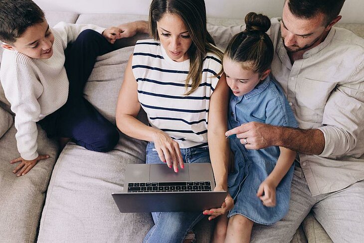 Parents et enfants planifient leurs vacances sur un ordinateur, moment convivial et complice.