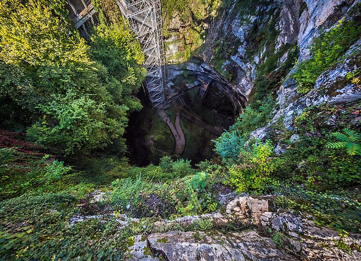 Vue plongeante du gouffre de Padirac, cavité spectaculaire entourée de falaises et végétation, site souterrain incontournable.