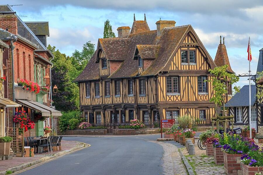 Une rue pittoresque bordée de maisons à colombages typiques dans le Calvados, représentant le charme et le patrimoine culturel unique de la Normandie, idéale à découvrir pendant un séjour en camping