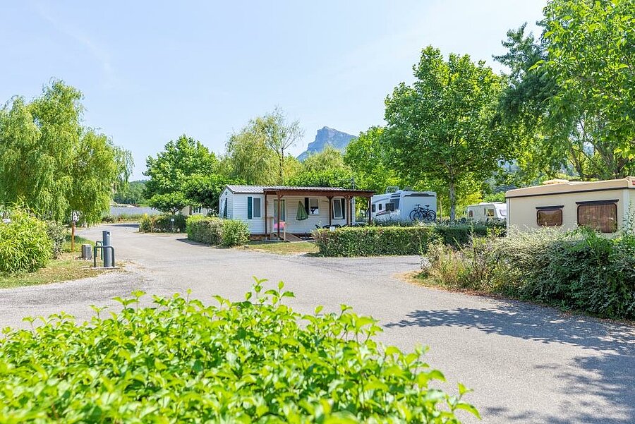Allée et hébergements du camping Les Prés Hauts à Sisteron, avec vue sur les Alpes