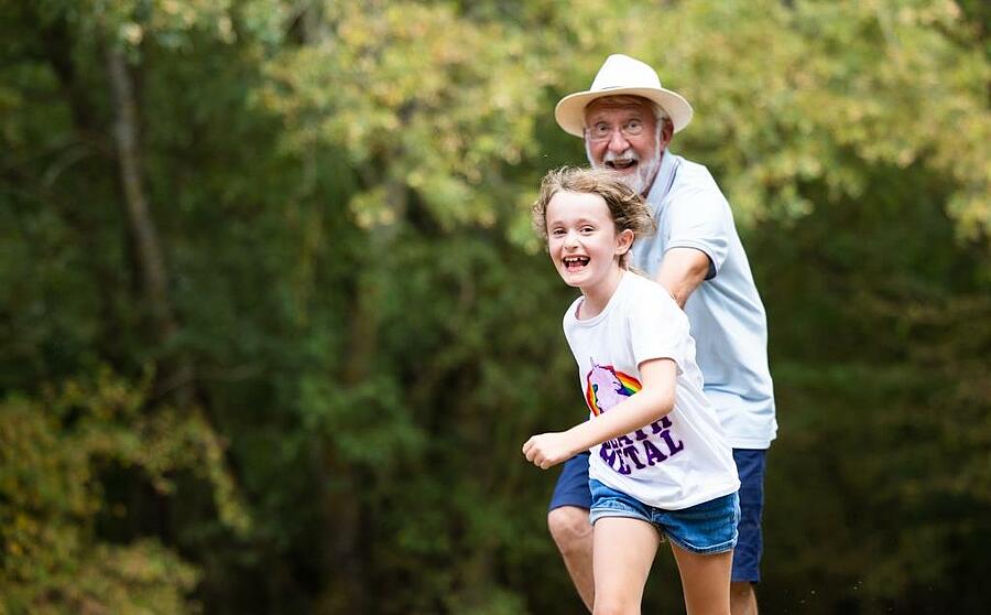 Grand-père et petite-fille courant joyeusement en plein air.