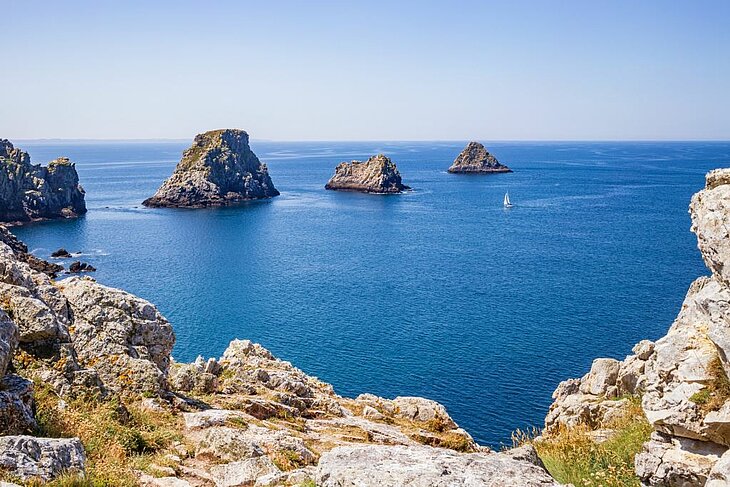 Presqu’île de Crozon : la Pointe de Pen-Hir et ses îlots rocheux Falaises de la Pointe de Pen-Hir sur la presqu’île de Crozon en Bretagne, îlots rocheux dans une mer calme, paysage emblématique à voir quand on se demande que faire en Bretagne.