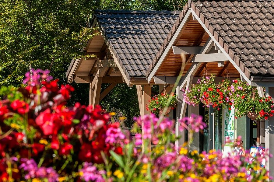 Entrée fleurie du camping à Clairvaux-les-Lacs, ambiance chaleureuse et naturelle pour des vacances dans le Jura.