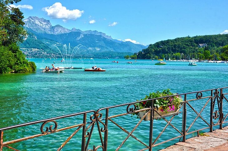 Vue sur le lac d’Annecy en Haute-Savoie, avec ses eaux turquoise et les montagnes en arrière-plan, un joyau d’Auvergne-Rhône-Alpes idéal pour des activités nautiques et des balades pittoresques.