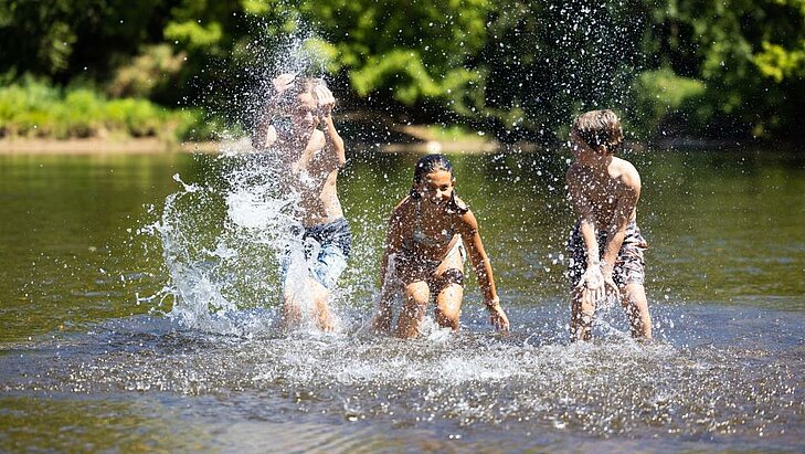 Vacances famille petit budget : profiter des activités nature gratuites Enfants jouant dans une rivière en pleine nature, activité gratuite idéale pour des vacances famille petit budget.