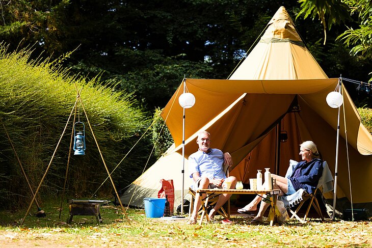 Couple profitant d’un hébergement en tente au camping Le Neptune à Lanloup, dans un cadre naturel paisible, reflet de la culture et du patrimoine local.