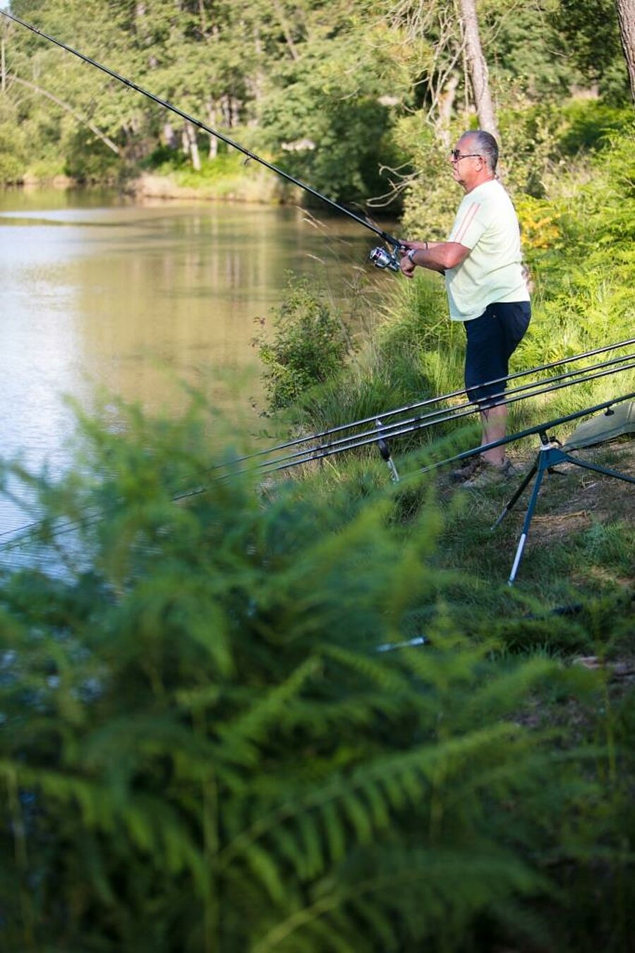 Homme pratiquant la pêche en bord de lac dans un camping Sites et Paysages, un moment de détente en pleine nature pour le week-end de l’Ascension.