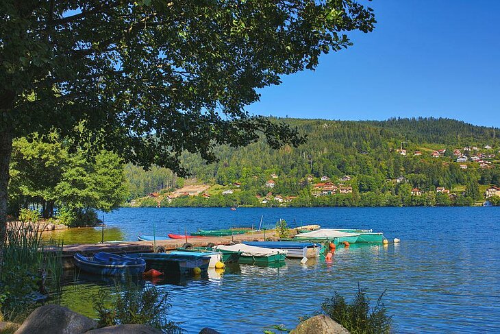 Barques amarrées sur le lac de Gérardmer entouré de montagnes verdoyantes, à deux pas de Corcieux, destination idéale pour un tourisme nature.