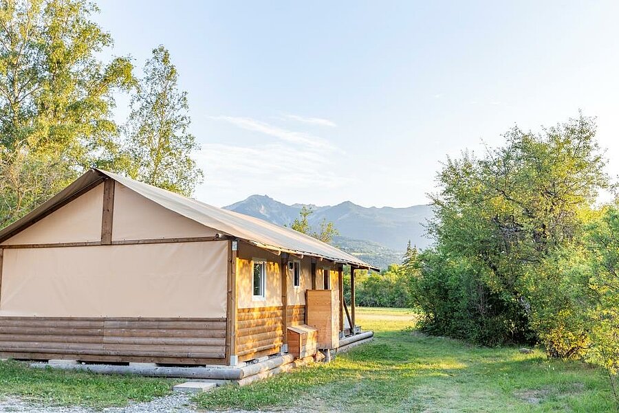 Tente lodge en bois dans un camping près du lac de Serre-Ponçon, offrant un hébergement confortable en pleine nature.