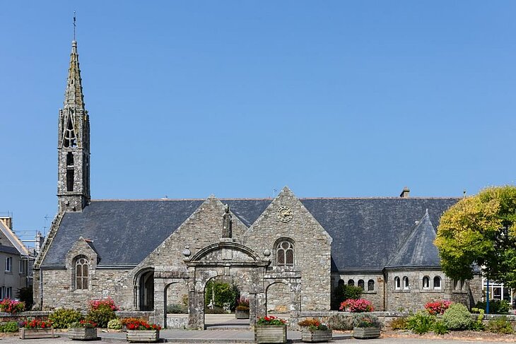 Façade en granit de l’église Saint-Magloire à Telgruc-sur-Mer, entourée de fleurs et symbole du patrimoine local.
