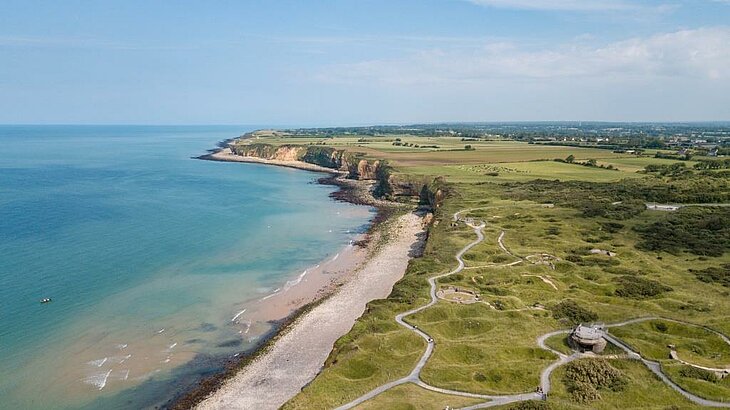 Plages du Débarquement Vue aérienne des plages du Débarquement en Normandie, falaises et vestiges du Mur de l’Atlantique, sortie culturelle en famille.