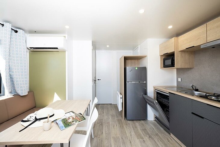 Le confort d’un mobil-home climatisé Pièce de vie et cuisine d’un mobil-home équipé d’un climatiseur mural