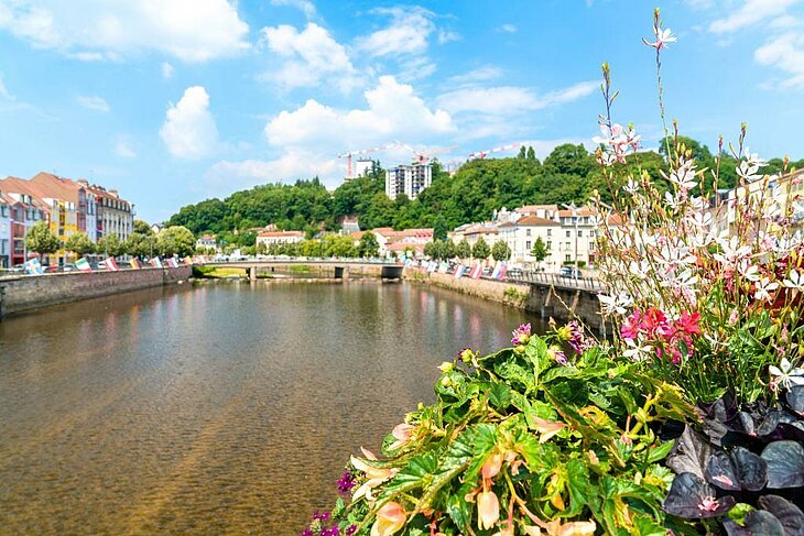 Vue d’Épinal avec ses quais fleuris et ses bâtiments colorés, illustrant le charme des cités de caractère dans les Vosges.