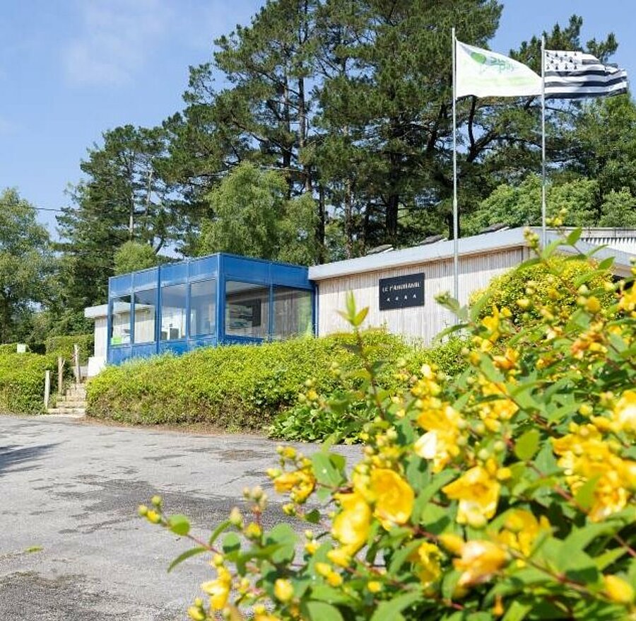 Réception du camping Le Panoramic près de Quimper, avec le drapeau breton, pour des vacances en pleine nature en Bretagne.