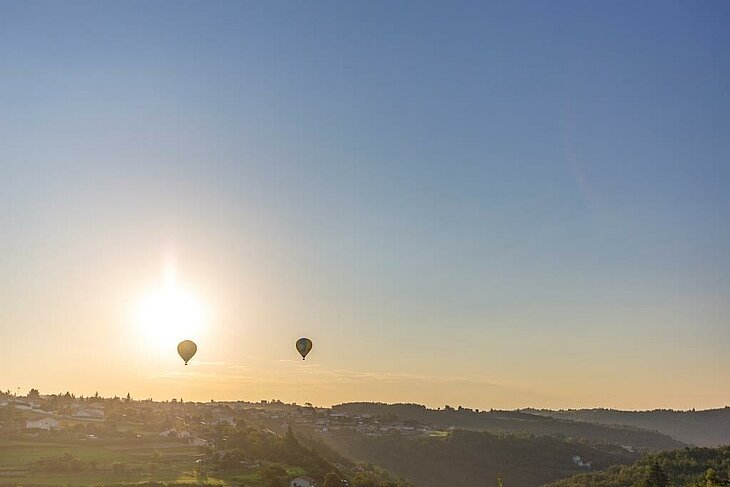 Deux montgolfières survolant les paysages au lever du soleil près d’Annonay, une expérience magique à vivre autour d’Eclassan pour les familles en quête d’émotions en pleine nature.