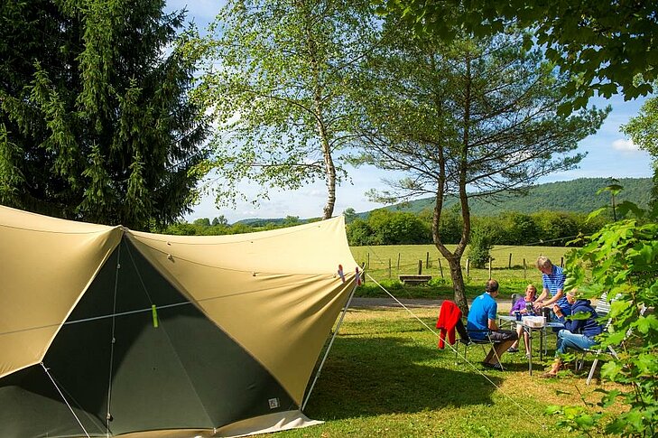 Famille installée sur un emplacement spacieux et verdoyant du camping Sites et Paysages Beauregard, pour une pause confortable autour de Mesnois.