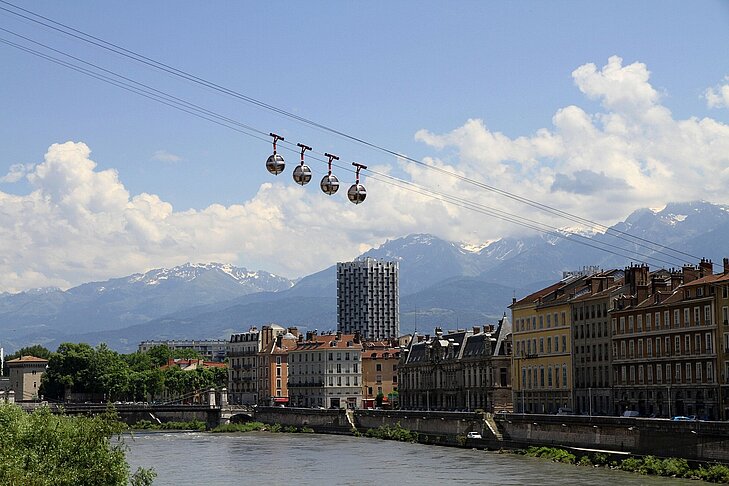 Vue sur le téléphérique de Grenoble avec les montagnes enneigées en arrière-plan, un symbole d’Auvergne-Rhône-Alpes et de l’Isère, entre ville et nature préservée.