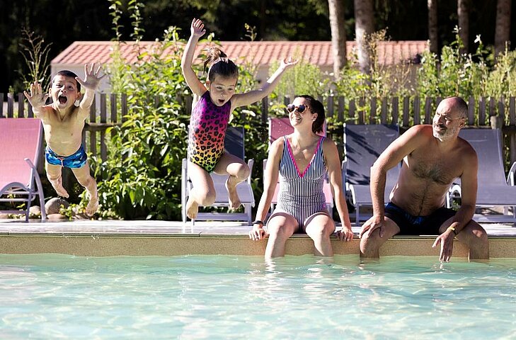 Vacances famille petit budget avec piscine et loisirs inclus Enfants sautant dans la piscine d’un camping pendant des vacances famille petit budget avec activités incluses.