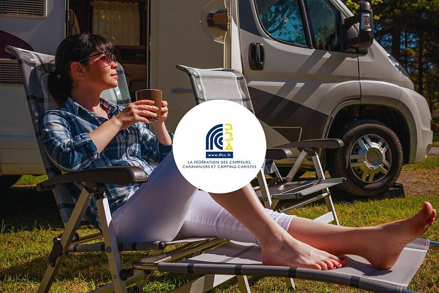 Campeuse installée devant son camping-car dans un camping nature Sites et Paysages, partenaire de la FFCC