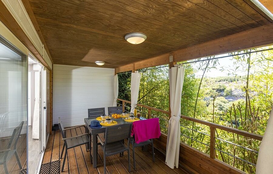 Terrasse en bois d’un mobil-home tout confort dans un camping près des gorges de l’Ardèche, idéale pour des repas en famille en pleine nature.